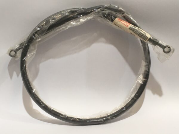 Latiguillo de freno negro enrollado con conectores en forma de ojo en ambos extremos, empaquetado en plástico transparente y una etiqueta con código de barras adherida.