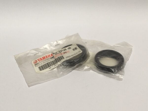 Two sealed parts labeled as "Retenes horquilla" from Yamaha are shown; one is inside a plastic bag and the other is on a white surface.