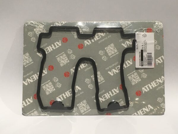 Two black rubber gaskets on an Athena brand packaging background, with a barcode label in the upper right corner. They appear to be rocker cover gasket components used for precision in engine assembly.