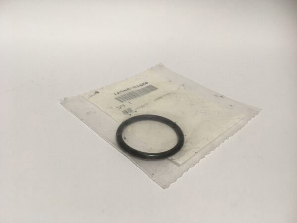 An O-ring, similar to an oil drain ring or plug, is placed on a transparent plastic bag with a white paper label underneath.