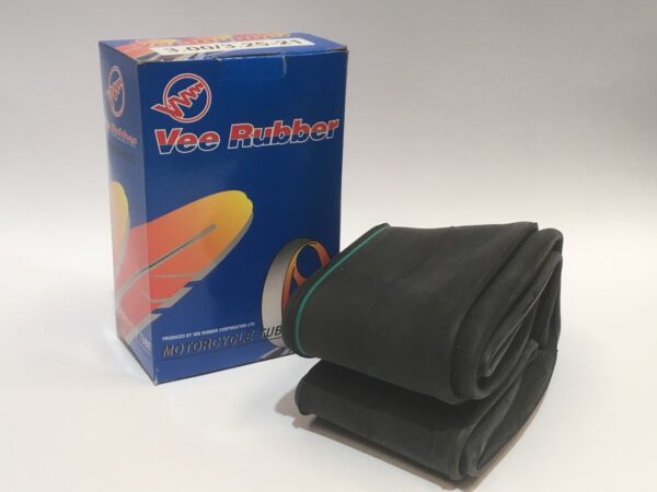 Una caja con la etiqueta "Vee Rubber" está junto a una cámara de rueda delantera 3.00-21 doblada, ideal para tu neumático negro.