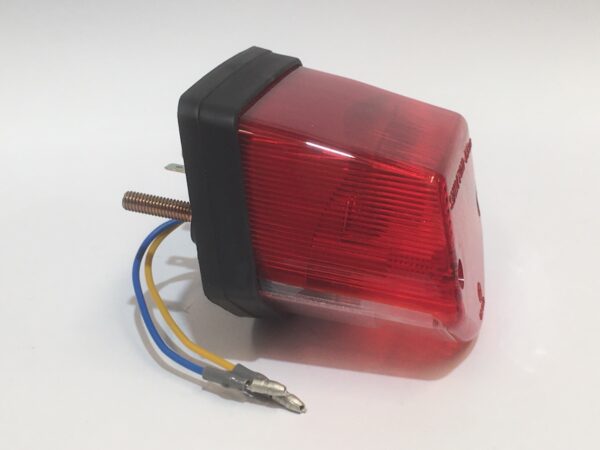 The complete rear light made of red plastic features two exposed wires and a metal bolt. It is presented on a white background, providing a comprehensive solution for your lighting needs.