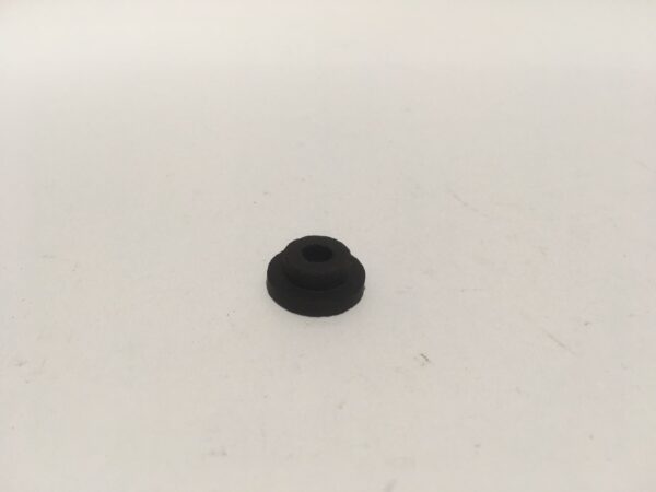 On a clean white surface rests a small black rubber piece called "Clock Mounting Rubber".