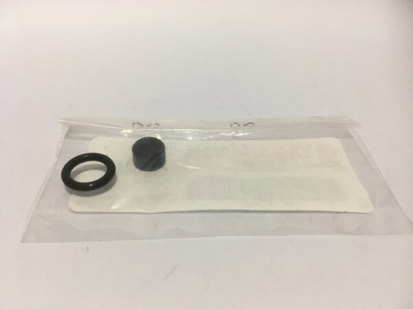 Inside a transparent plastic bag with a white label, there is a black rubber ring and a small black cylindrical object, which appear to be parts of an oil pump. The product name is "Oil Pump Gaskets". Everything is on a simple white background.