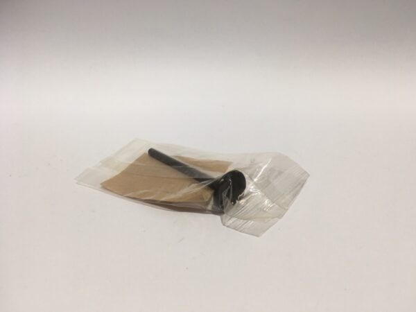 A small black cylindrical exhaust valve is placed inside a clear plastic bag on a pristine white surface.