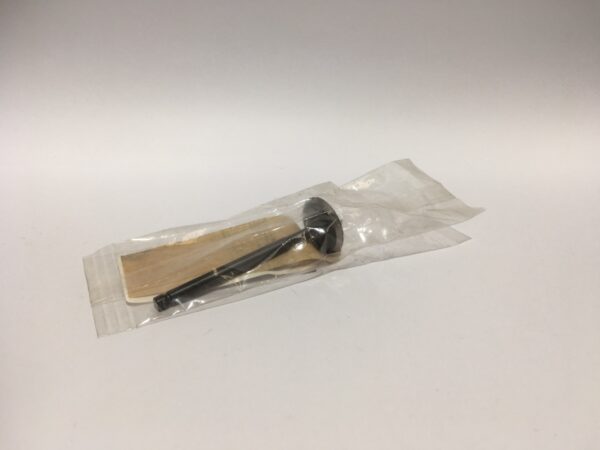 Una cuchara y un palito de madera para remover, envueltos cuidadosamente en celofán sobre un fondo neutro, reflejando la simplicidad característica de la Válvula de admisión.